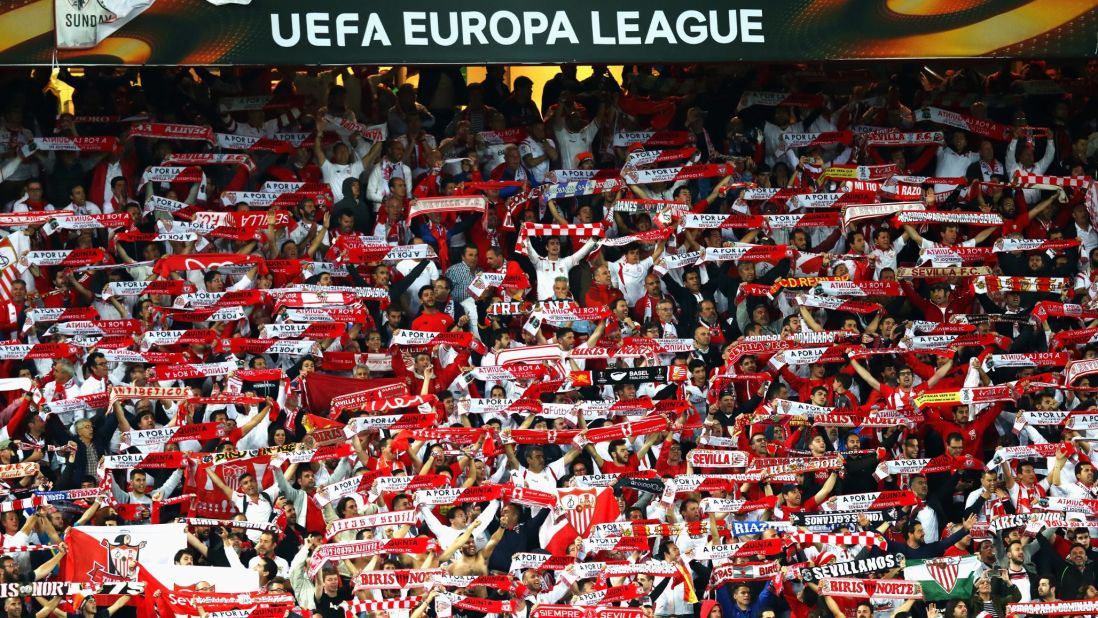Sevilla supporters cheer and hold up scarves as it becomes clear their team is about to claim another Europa League success.
