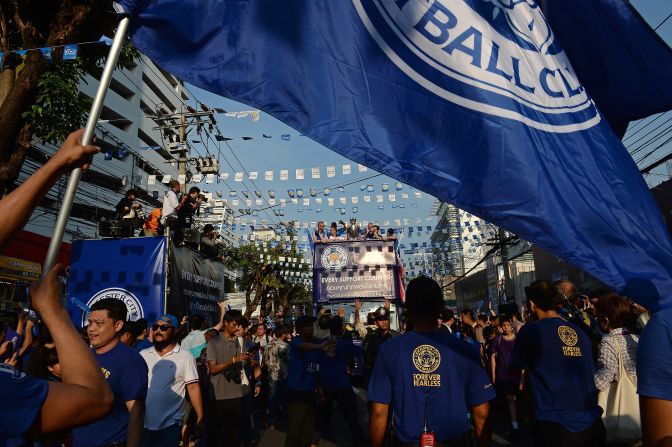 Fans wave a giant flag as Leicester's football players and owners parade through the streets of Bangkok on an open-top bus.