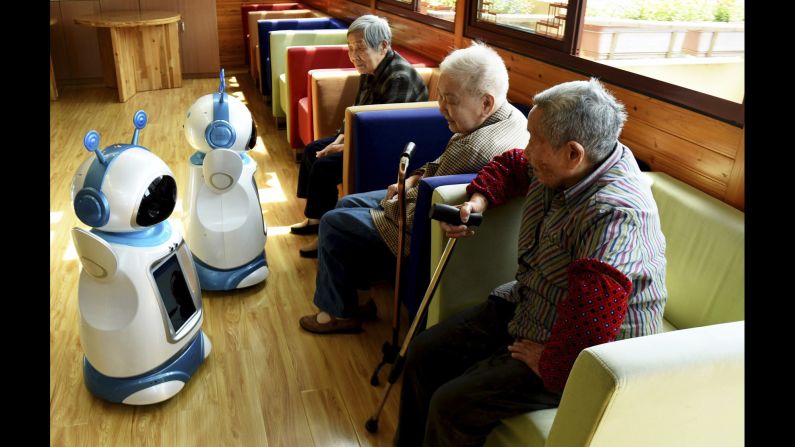Retirees look at Ah Tie robots at a nursing home in Hangzhou, China, on Tuesday, Nay 17. The robots were designed for nursing homes and are capable of monitoring vital signs. They can also be used for video conferencing.
