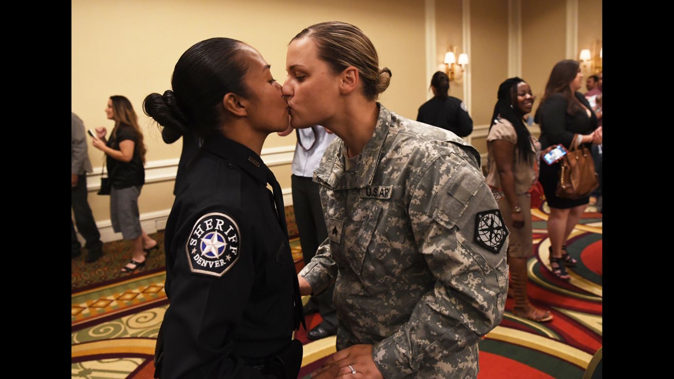 U.S. Army Sgt. Kathryn Fermin-Weinreb, right, kisses her wife, Victoria, after Victoria graduated from the Denver Sheriff Department's training academy on Friday, May 13.