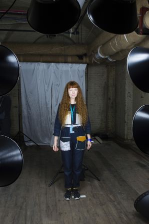 Artist Zoniel stands in front of the large bright lights of their Tintype camera. Each subject is required to stand for up to 30 seconds without moving for the image to be captured. To prepare and calm them for this intense experience, Zoniel (using her background in Buddhism) first talks them though a gentle meditation. 