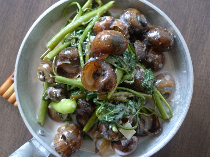 Fresh snails cooked in coconut milk and leafy vegetables are served in the shell, while a tiny fork (or toothpick) is used to loosen the meat inside.