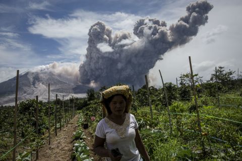 Smoke from Mount Sinabung billows behind a woman in June 2015. 