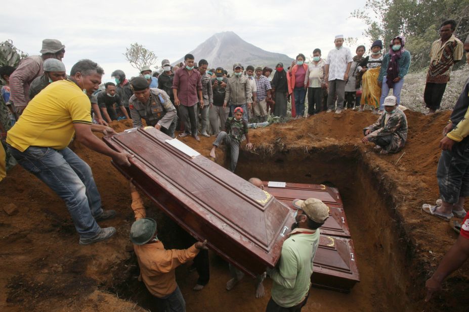 Coffins containing the bodies of the volcano eruption victims are lowered into a grave during a funeral Sunday, May 22.