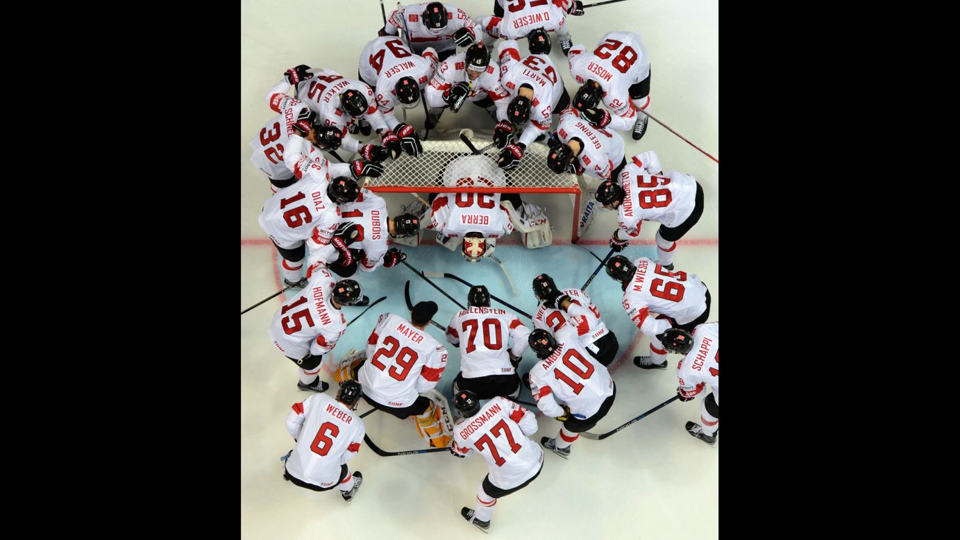 Swiss hockey players surround goalie Reto Berra before a game at the World Championships on Tuesday, May 17.