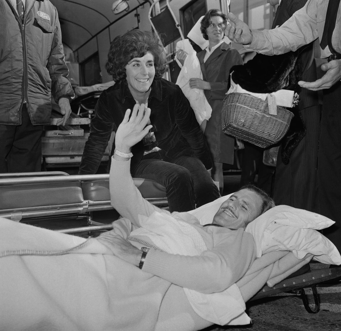 Oct 1969: An incapacitated Hill returns home to the UK from the U.S. alongside wife, Bette (C).