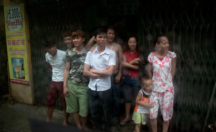 People gather in the rain to watch Obama's motorcade in Hanoi on May 24.