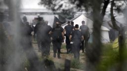 Greek policemen walk at a makeshift refugee camp at the Greek-Macedonian border near the northern village of Idomeni, Tuesday, May 24, 2016. Greek authorities have begun an operation to gradually evacuate the country's largest informal refugee camp of Idomeni, located on the Greek-Macedonian border, where more than an estimated 8,400 people have been living for months. (AP Photo/Boris Grdanoski)