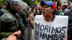 TOPSHOT - A woman with a sign reading "We starve" protests against new emergency powers decreed this week by President Nicolas Maduro in front of a line of riot policemen in Caracas on May 18, 2016. 
Public outrage was expected to spill onto the streets of Venezuela Wednesday, with planned nationwide protests marking a new low point in Maduro's unpopular rule. / AFP / FEDERICO PARRA        (Photo credit should read FEDERICO PARRA/AFP/Getty Images)