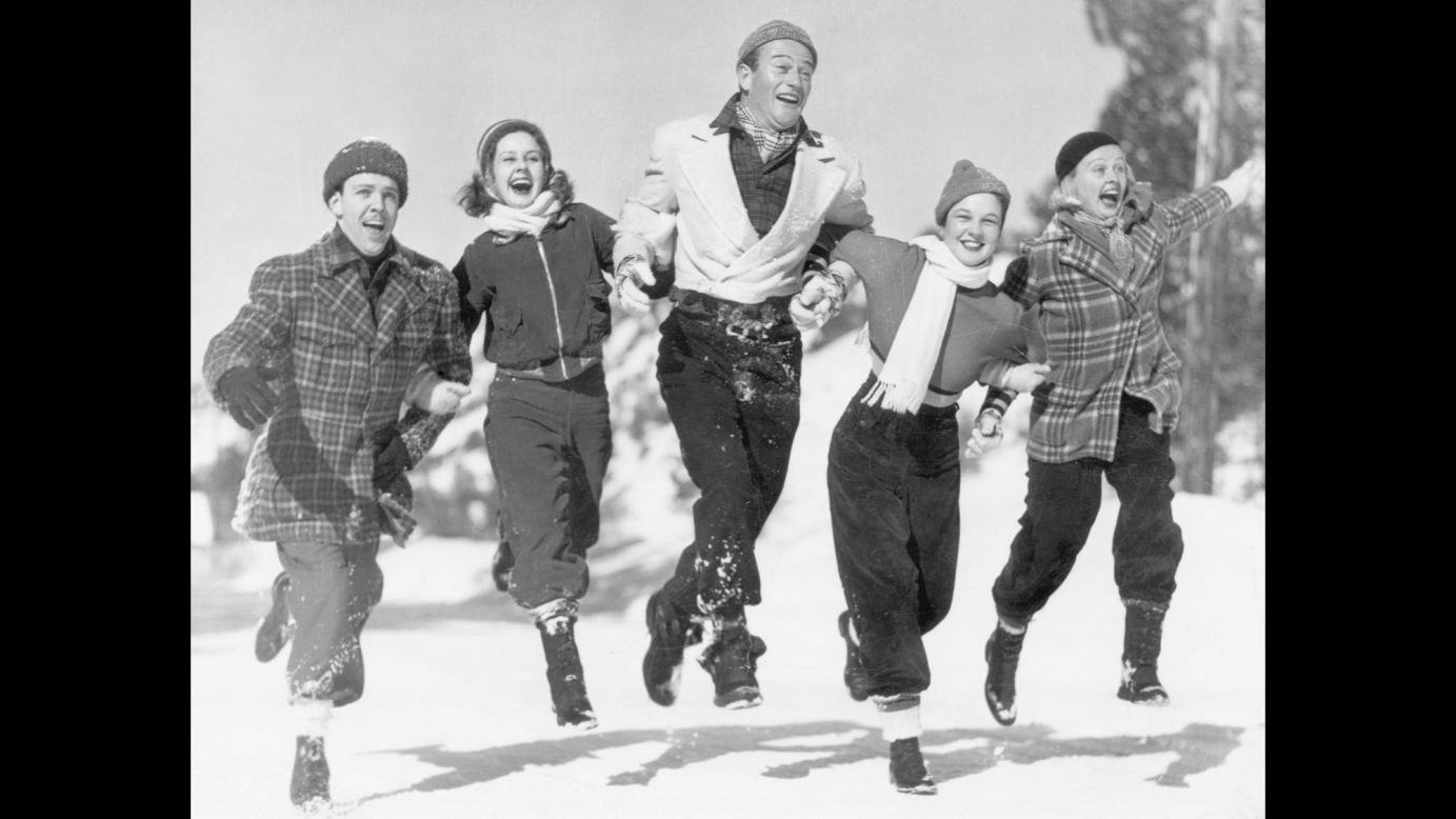 Wayne and other actors from Universal Studios visit a winter resort in Big Pines, California, in 1937. From left are Michael Fitzmaurice, Barbara Read, Wayne, Fay Cotton and Emily Lane.