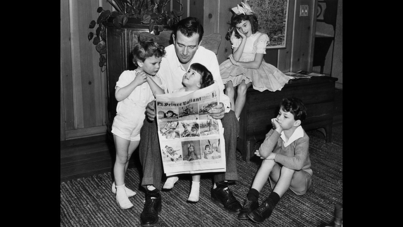 Wayne reads a comic with his four children in 1942. Wayne's children, from left, are Patrick, Melinda, Toni and Michael. He would father three more children in a later marriage.