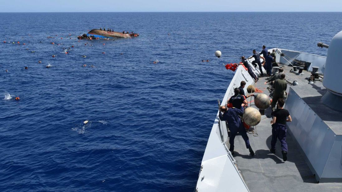 Italian sailors prepare to toss floatation devices into the water from their ship.