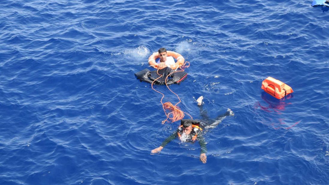 A migrant uses a buoy to stay afloat in the water.