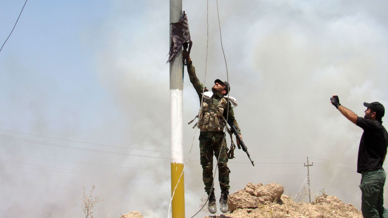A fighter with the Badr Brigades, a Shiite militia, takes an ISIS flag down outside Falluja on May 23.