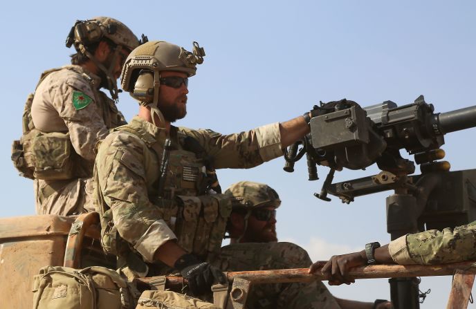 Armed men in uniform identified by Syrian Democratic forces as U.S. special operations forces ride in the back of a pickup truck in the village of Fatisah in the northern Syrian province of Raqqa on May 25, 2016. The Syrian Democratic Forces (SDF) announced on May 24 its push for IS territory north of Raqa city.