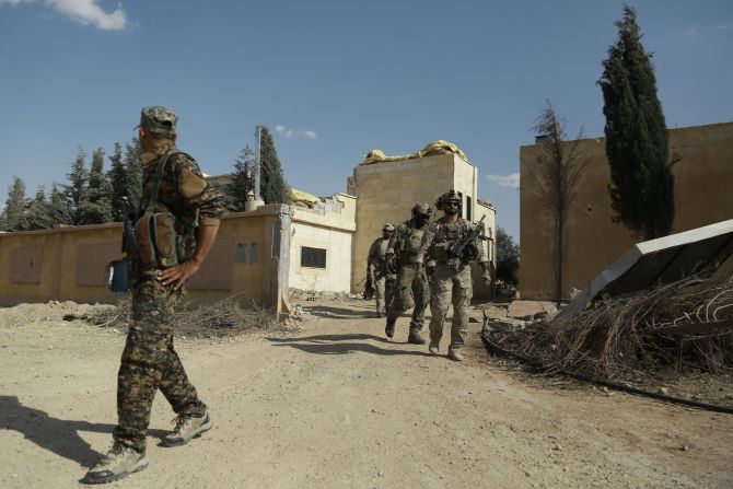 Armed men in uniform (R) identified by Syrian Democratic forces as U.S. special operations forces walk in the village of Fatisah in the northern Syrian province of Raqqa on May 25, 2016. U.S.-backed Syrian fighters and Iraqi forces pressed twin assaults against the Islamic State group, in two of the most important ground offensives yet against the jihadists.
