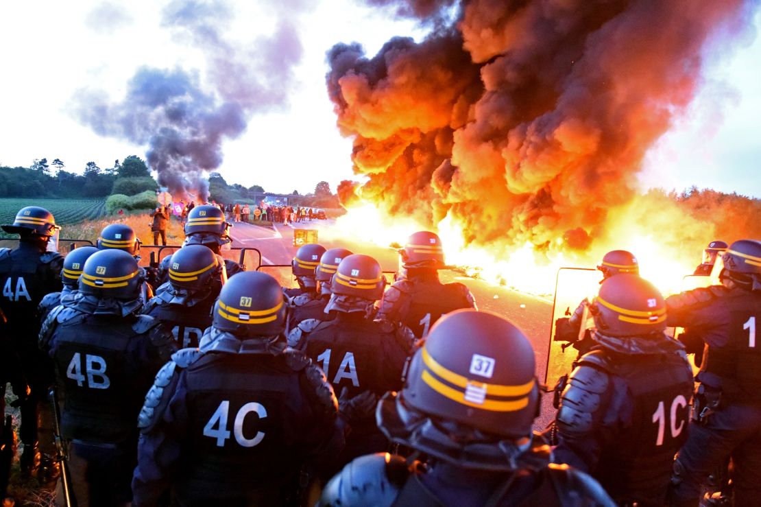 Riot police stand guard as workers at an oil refinery burn tires and blockade an oil depot in Douchy-Les-Mines, France, on May 25 to protest proposed changes to labor laws.