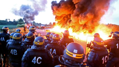 Riot police stand guard as workers at an oil refinery burn tires and blockade an oil depot in Douchy-Les-Mines, France, on May 25 to protest proposed changes to labor laws.