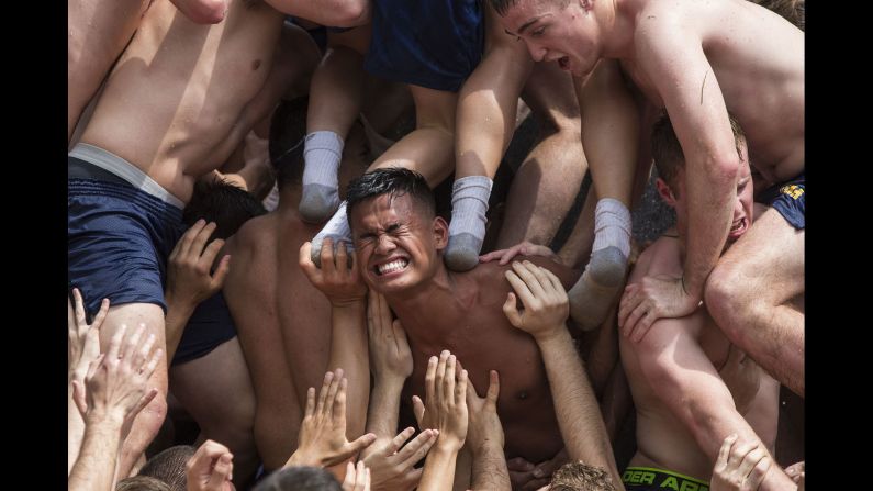 Plebes climb the Herndon Monument to end their first year at the U.S. Naval Academy on Monday, May 23. The midshipmen have to work together to climb the 21-foot monument, covered in vegetable shortening, so they can replace the cap on top.