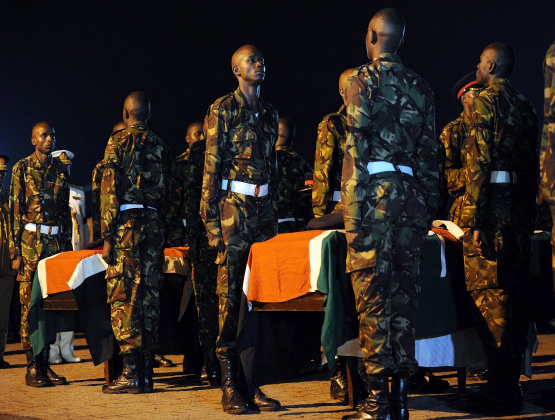 Kenyan soldiers stand over caskets bearing the remains of four slain comrades.