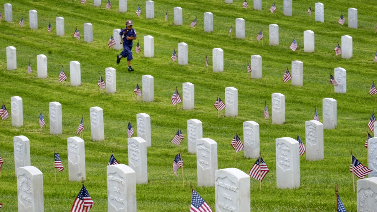 A Boy Scout runs past gravestones after volunteers placed American flags at the Los Angeles National Cemetery on Saturday, May 28.