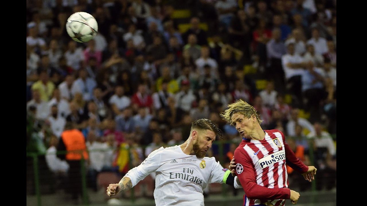 Atletico Madrid forward Torres heads the ball past Real Madrid defender Ramos.