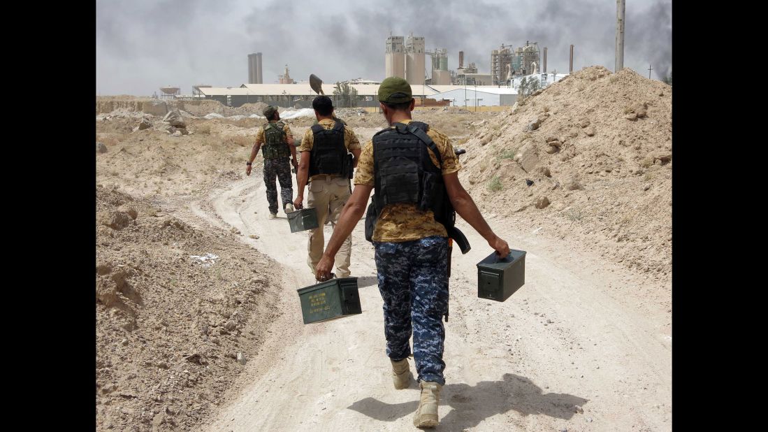 Pro-Iraqi government fighters carry ammunition in the village of Harariyat on Saturday, May 28.