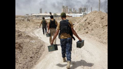 Pro-Iraqi government fighters carry ammunition in the village of Harariyat on Saturday, May 28.