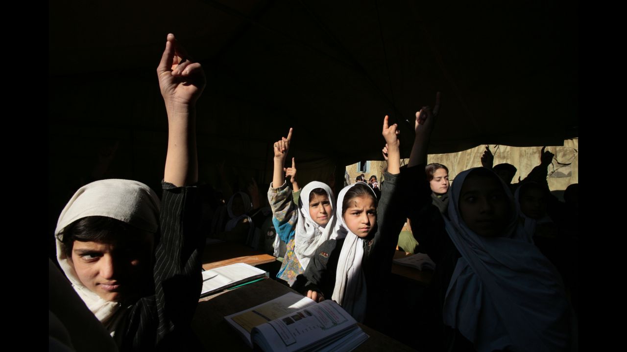 Afghan girls raise their hands during English class at the Bibi Mahroo high school in Kabul in November 2006. The overcrowded school was made up of UNICEF-supplied tents.