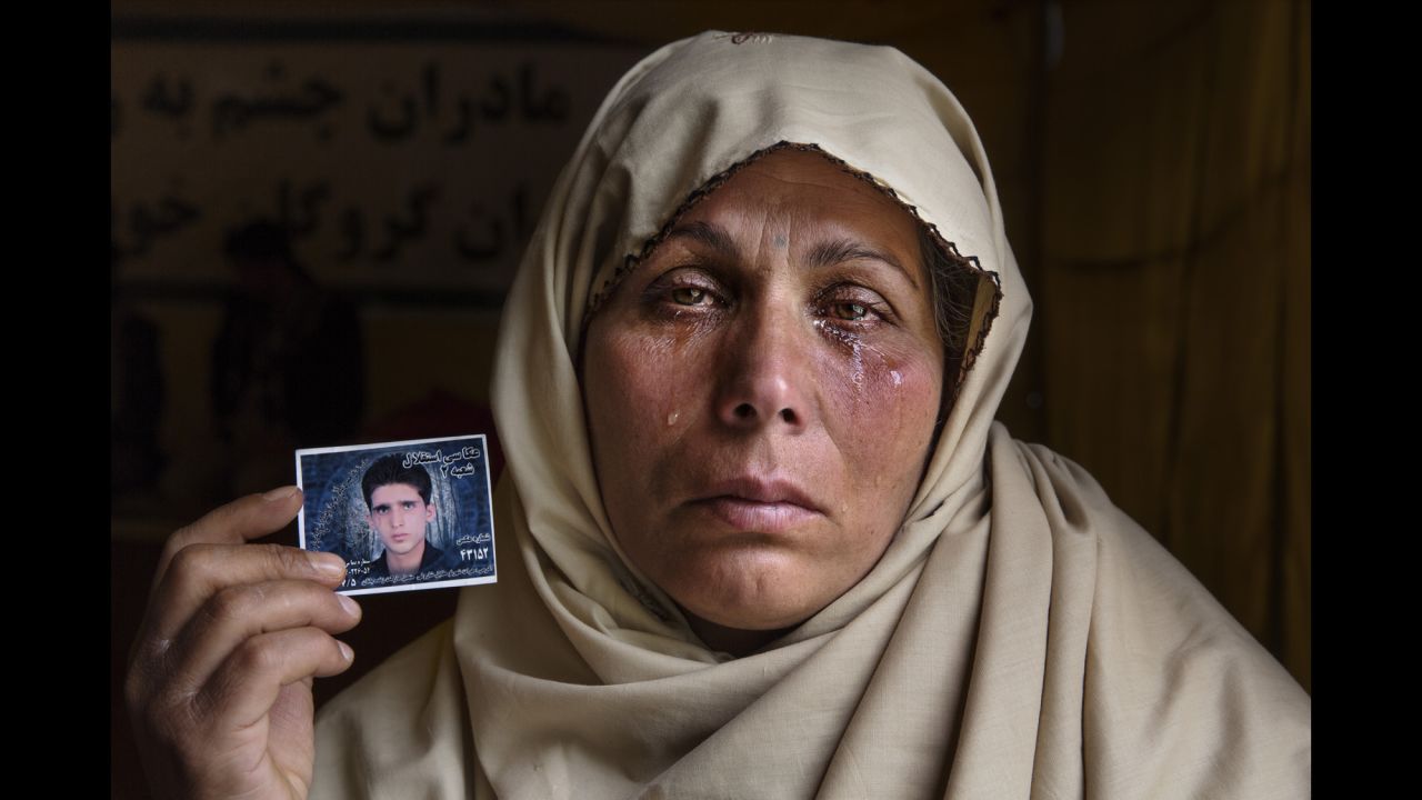 Bibi Aisha cries in April 2015 as she holds a photo of her 22-year-old son, Yousef, who was kidnapped. After many weeks with no answer, she worried he would be killed.