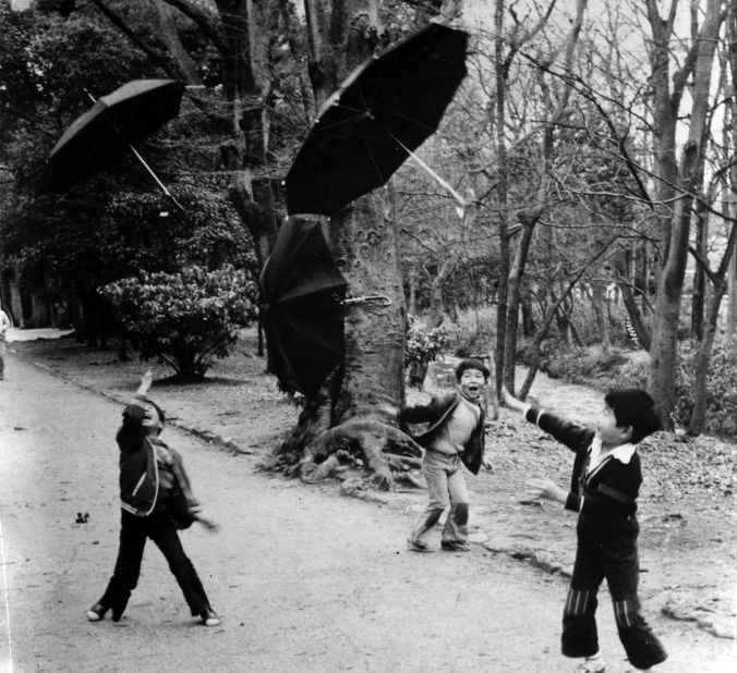 Fusayoshi has been documenting Kyoto life since the 1970s. Pictured, three kids in a forest enjoying throwing umbrellas under typhoon winds.