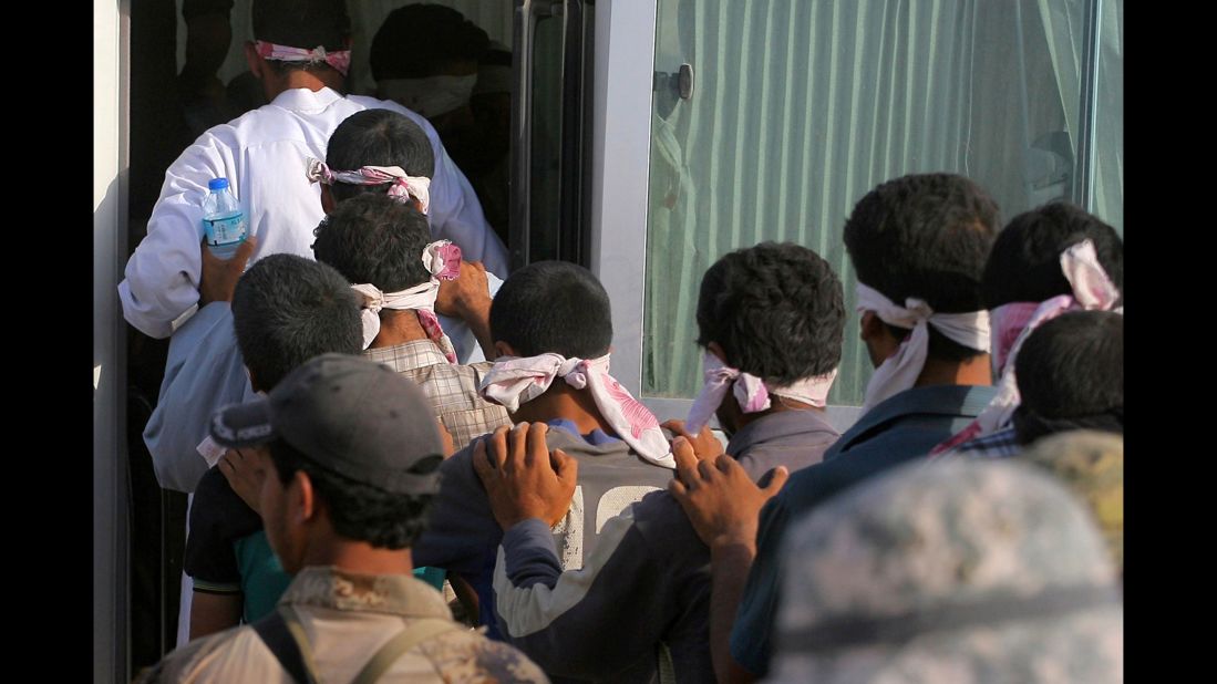 Blindfolded men get led to a bus after being detained during the fighting on June 1.