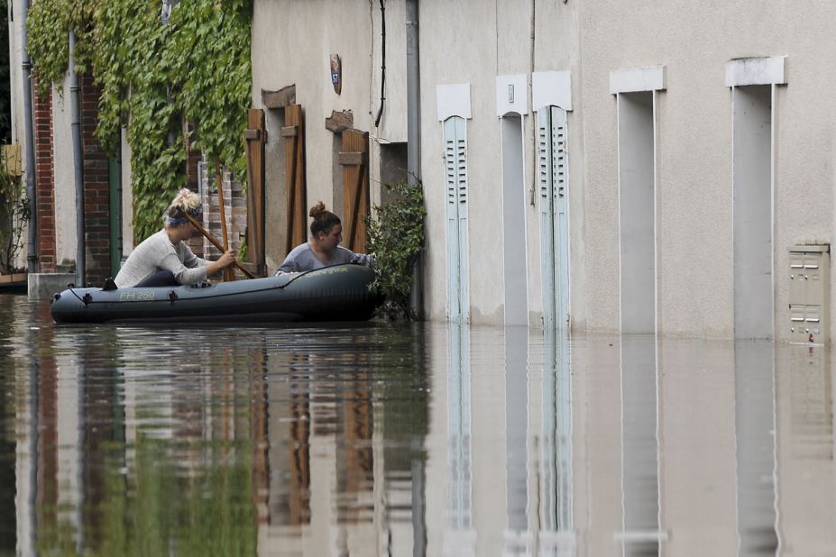 Two women try to enter their flooded home from an inflatable raft in Montargis on June 1.