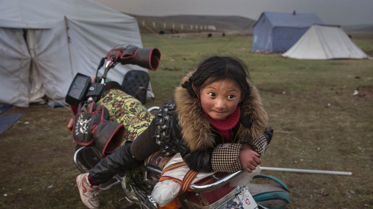 A Tibetan nomad girl rests on a motorcycle at a temporary camp for picking cordycep fungus on May 22, 2016.