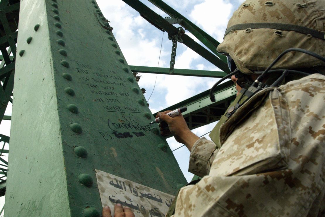 During the second battle of Falluja in November 2004, a Marine writes a message on the bridge over the Euphrates where the charred bodies of American contractors were hung.