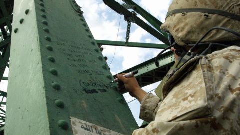 During the second battle of Falluja in November 2004, a Marine writes a message on the bridge over the Euphrates where the charred bodies of American contractors were hung.
