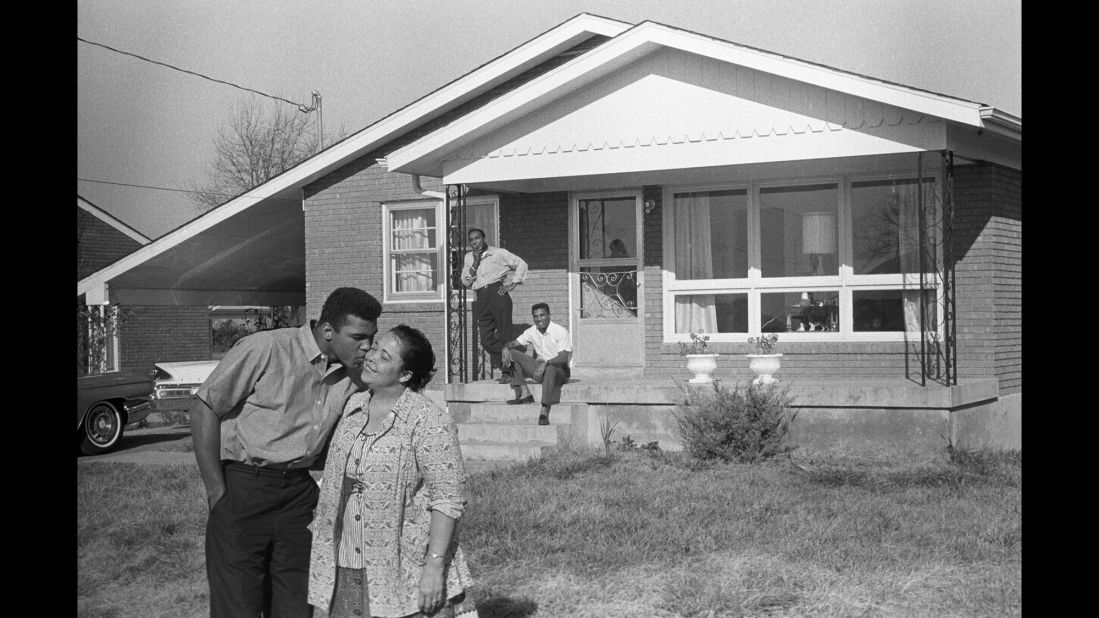 Muhammad Ali, whose birth name was Cassius Clay, kisses his mother, Odessa, in front of the family's Louisville, Kentucky, home in 1963, as his father, Cassius Clay Sr., and brother, Rudy, look on.  Ali changed his name in 1964 after converting to Islam.  