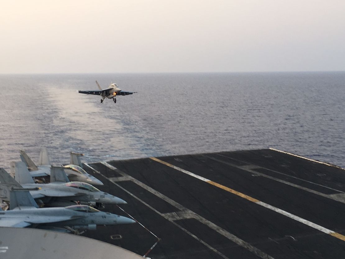 An F/A-18 Hornet comes in to land on the deck of the Truman after a mission against ISIS. Its empty wings indicate bombs have been dropped.