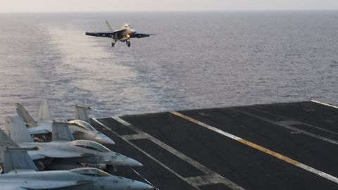 An F/A-18 Hornet comes in to land on the deck of the Truman after a mission against ISIS. Its empty wings indicate bombs have been dropped.