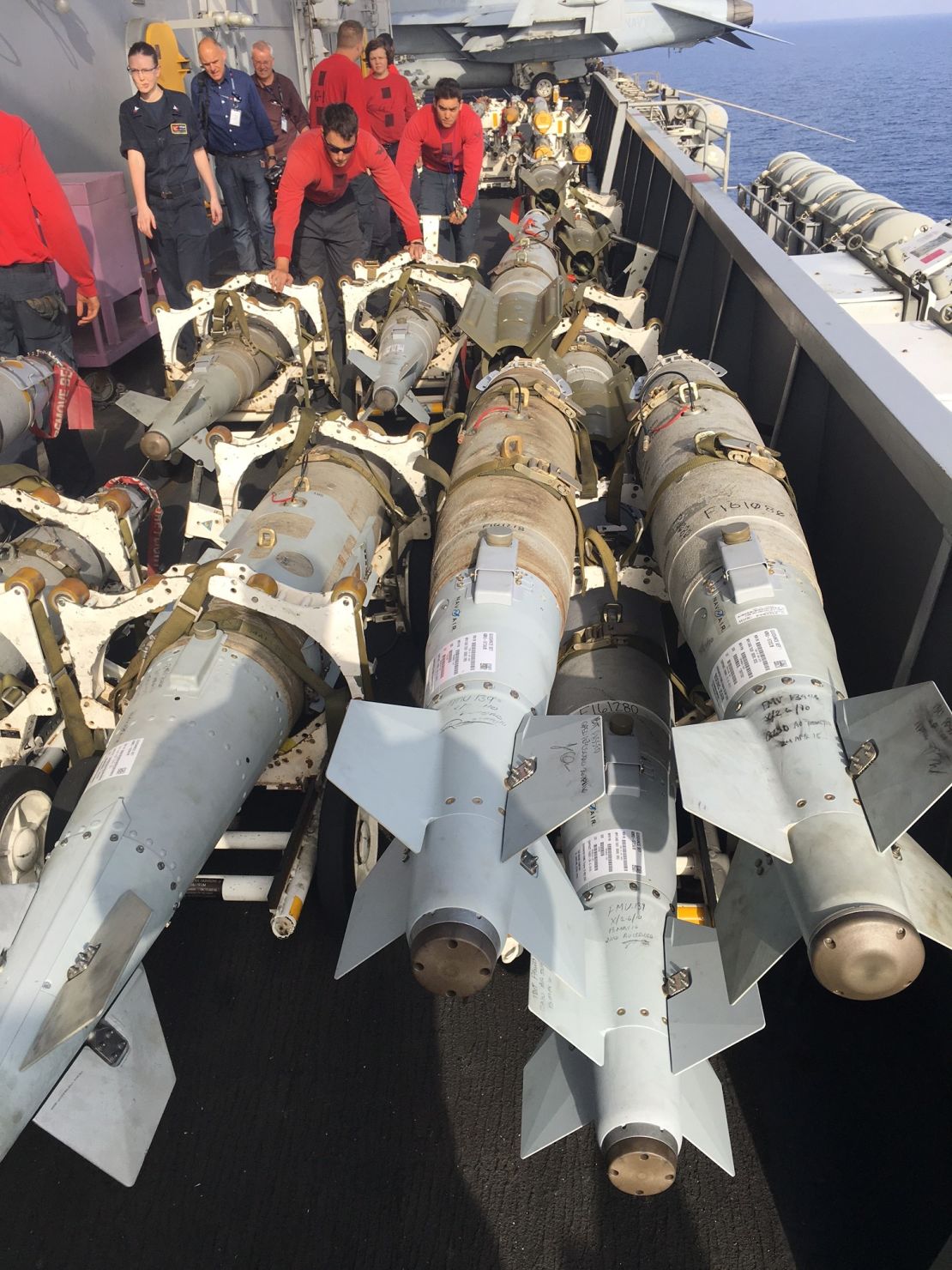 Crew members haul fully assembled guided bombs across the Truman's deck. 