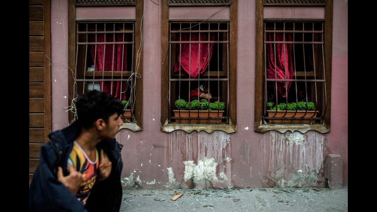 A man walks past a building with broken windows from the blast.