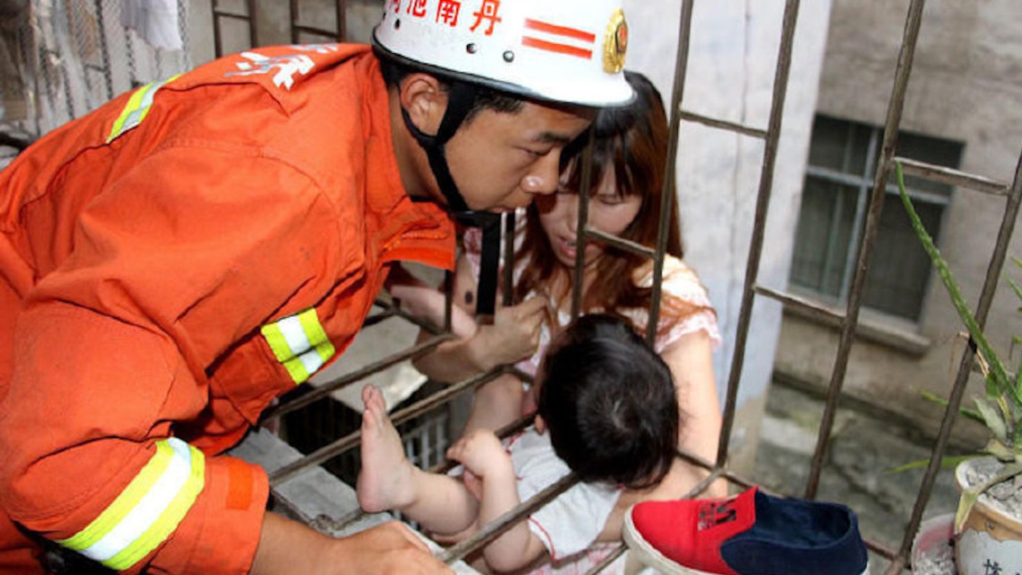 Firefighters in China rescued a three-year-old girl who fell through a gap in a second-floor balcony.
