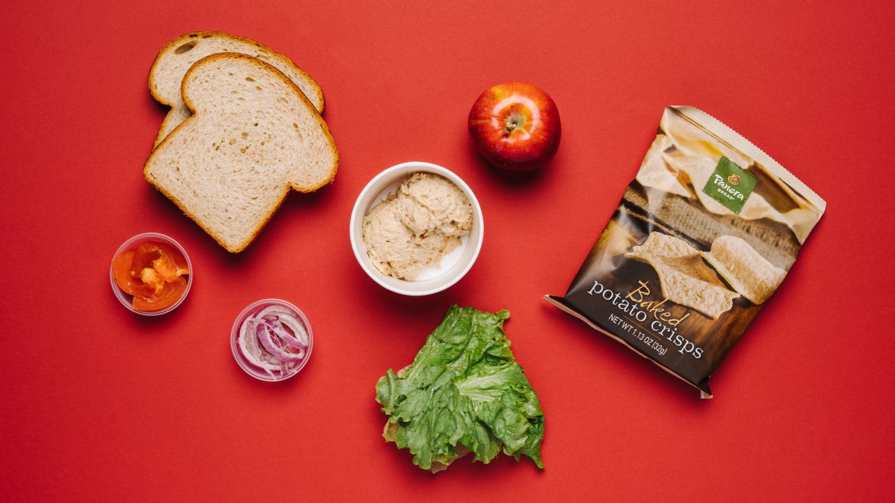 Healthy food that's easy to eat while driving is found in the tuna salad sandwich on honey wheat with apple and baked crisps.