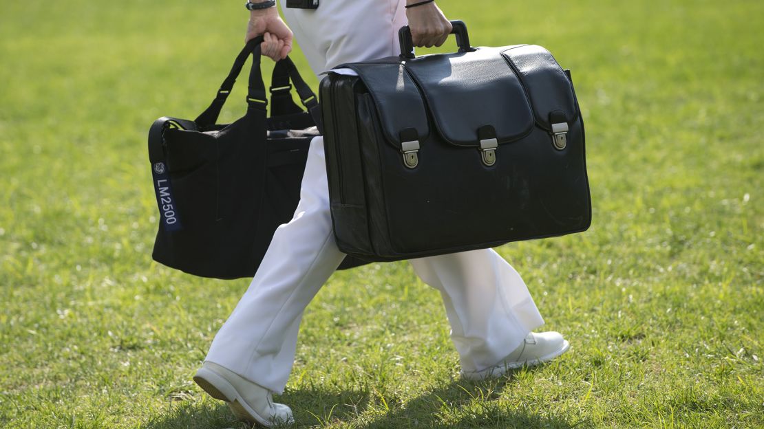 A White House military aide and member of the US Navy carries a briefcase known as the "football," containing emergency nuclear weapon codes, as then-President Barack Obama departs from the White House in 2012. 