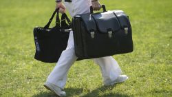 A White House military aide and member of the US Navy carries a briefcase known as the "football," containing emergency nuclear weapon codes, as US President Barack Obama departs on Marine One from the South Lawn of the White House in 2012.