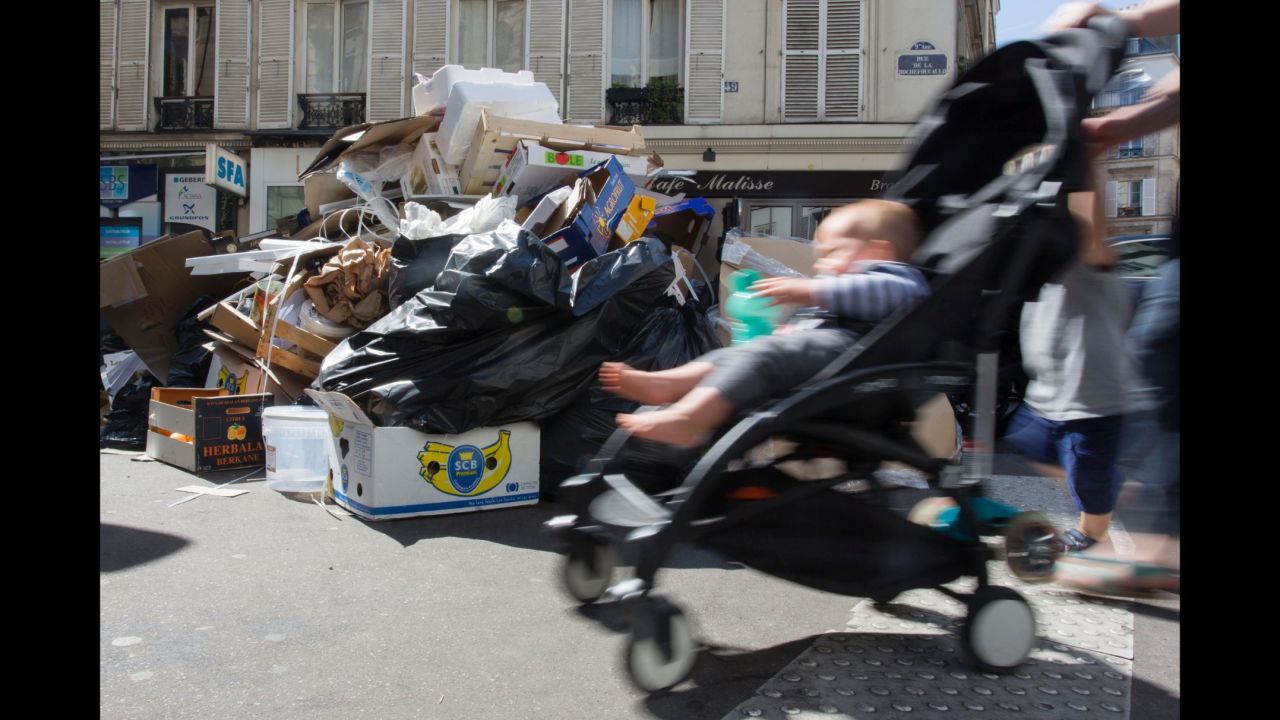 A Parisian pushes a stroller in front of rubbish bins in the Pigalle district on June 9.