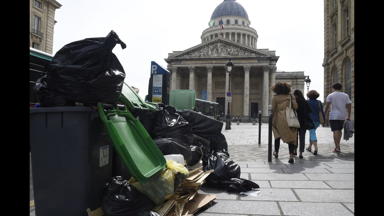 Pedestrians walk past rubbish bins on the pavement near the Panthéon in Paris on Friday, June 10. During nationwide strikes over labor reforms, garbage workers are refusing to pick up trash.