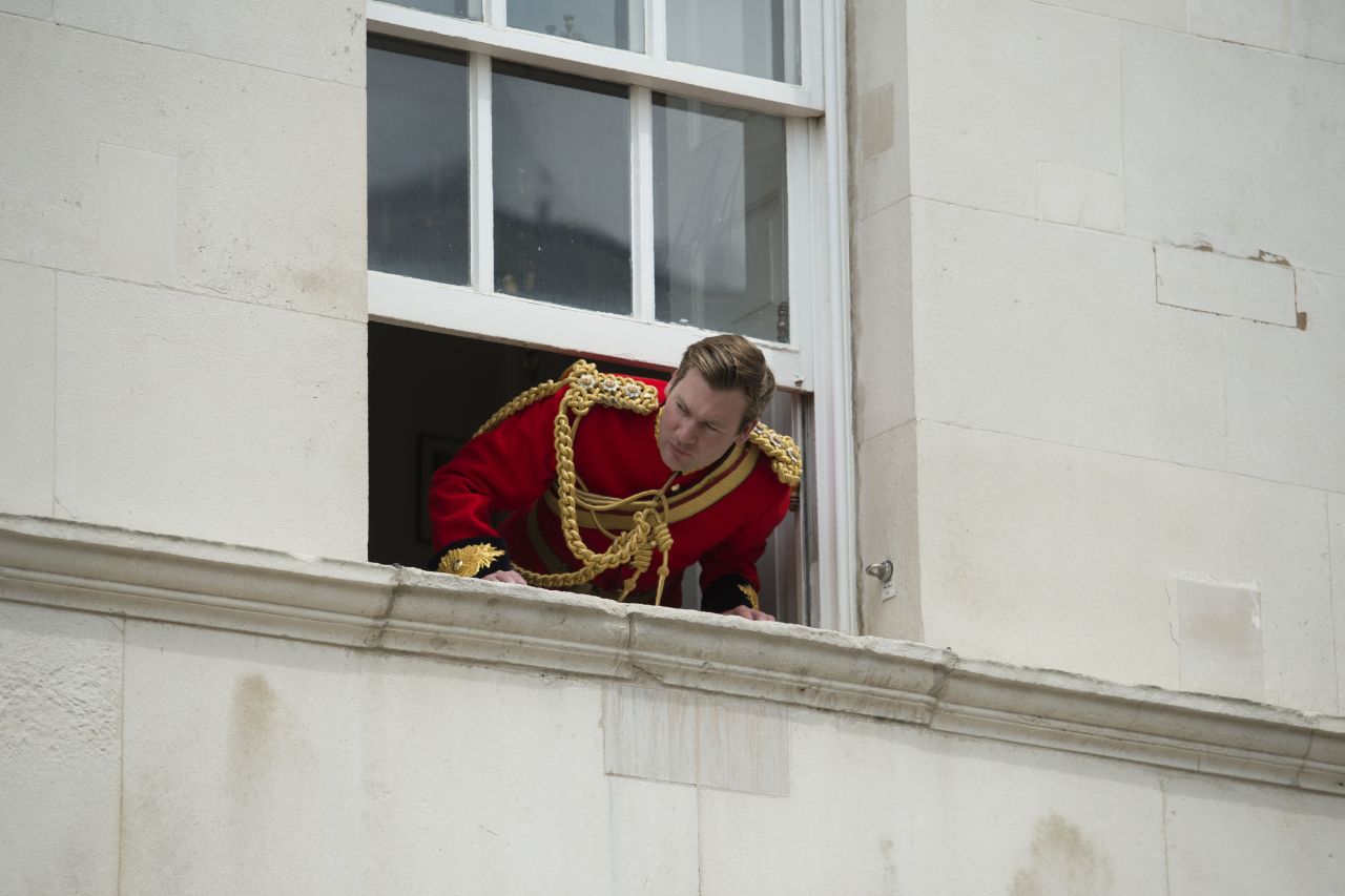A soldier looks out of an upper floor window to watch the parade.
