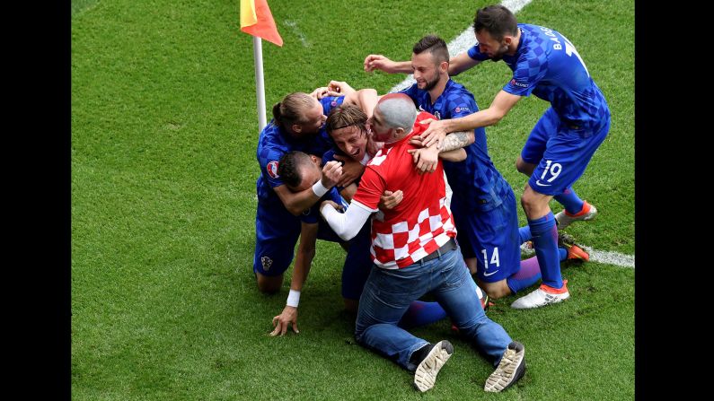A fan enters the pitch to celebrate with Modric after the goal.