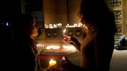 Two woman light candle during a vigil in front of the U.S. embassy to remember the victims of the mass shooting at the Pulse Orlando, Fla. nightclub, in Santiago, Chile, Sunday, June 12, 2016. A gunman opened fire inside the nightclub early Sunday, killing at least 50 people before dying in a gunfight with SWAT officers, police said. (AP Photo/Esteban Felix)
